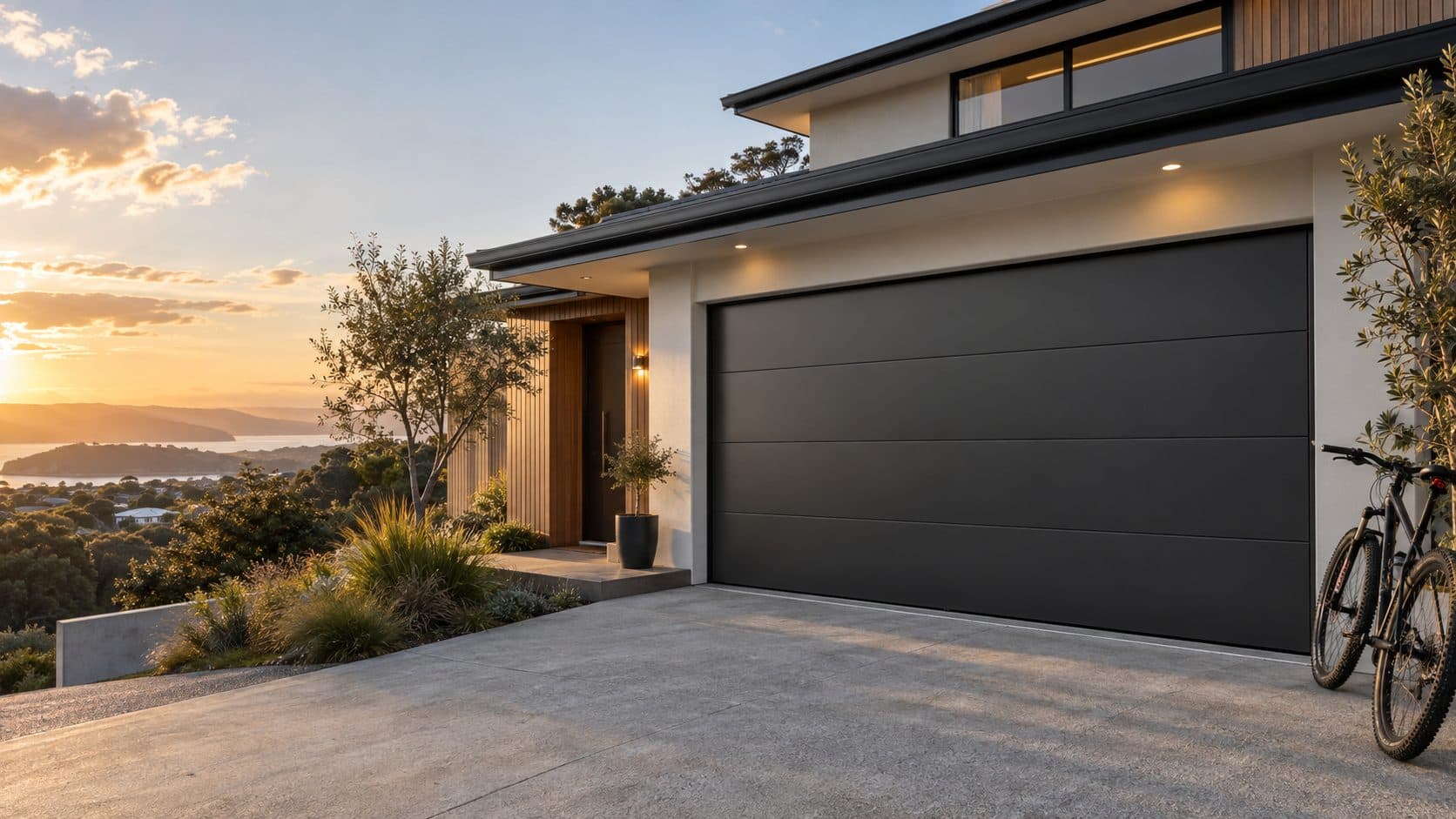 A new dark sectional garage door on a North Auckland home at sunset